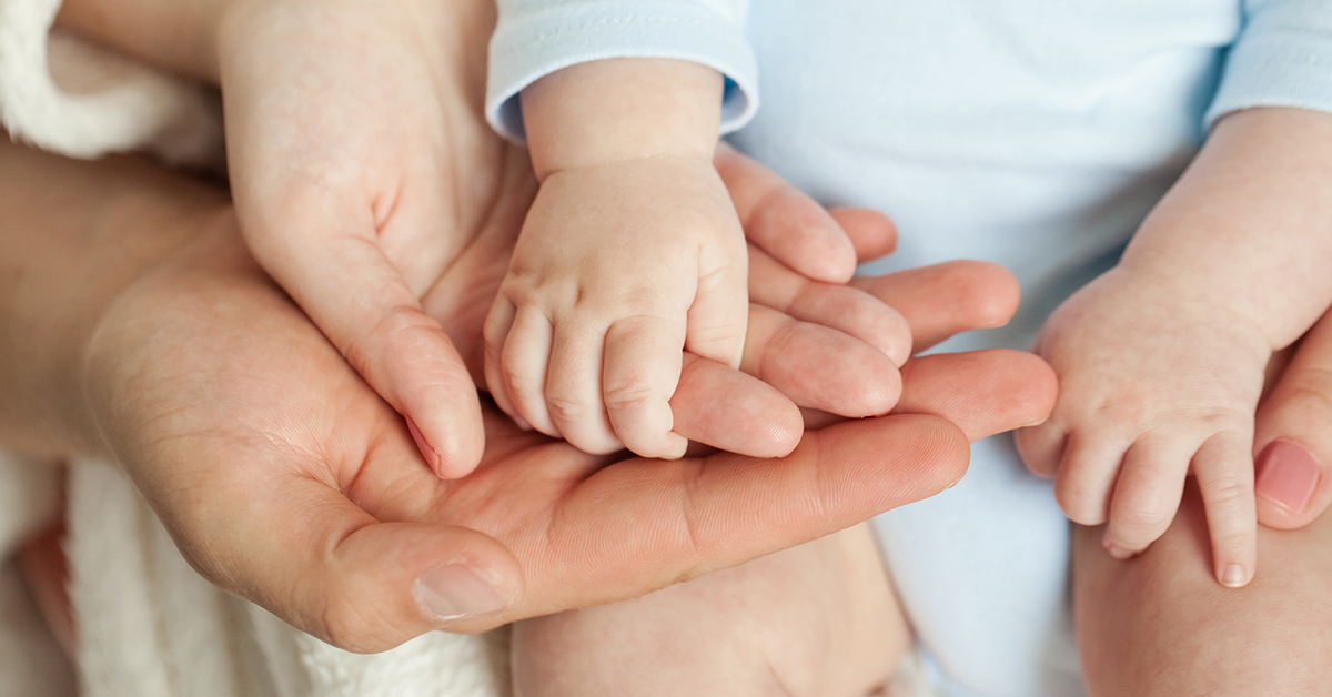 Vauvan kädet ja kahden aikuisen kädet.